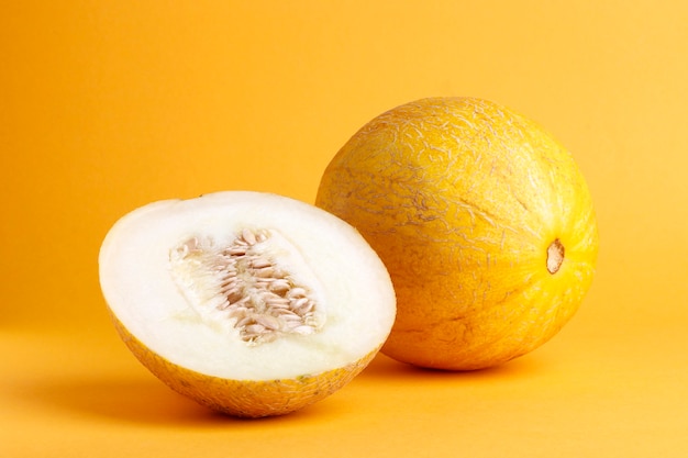 Melone fresco maturo su sfondo arancione. Un pezzo di melone tagliato a metà. piatto laÃÂ'Ã‚Âƒ