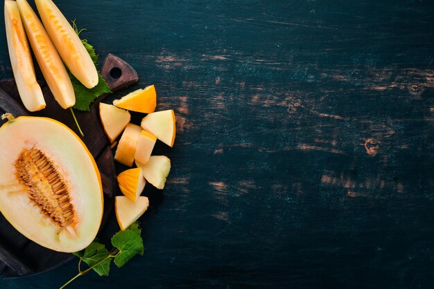 Melone fresco Tagliato a pezzi di melone Su uno sfondo di legno nero Spazio libero per il testo Vista dall'alto