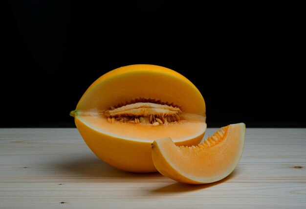 Melone giallo dolce fresco la tavola di legno su fondo nero