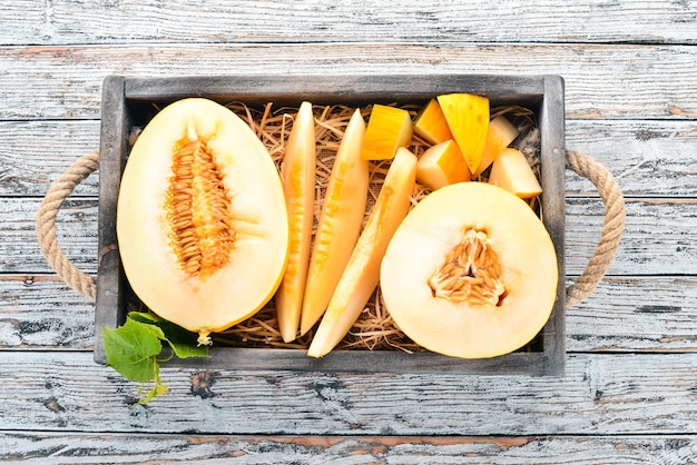 Melone in una scatola di legno Tagliato a pezzi di melone Su uno sfondo di legno Spazio libero per il testo Vista dall'alto