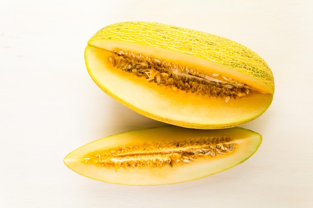 Melone persiano biologico affettato su tavola di legno bianco.