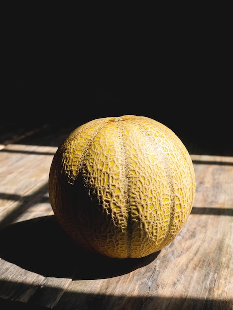 Melone rotondo isolato su un tavolo di legno