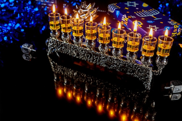 Menorah con candele accese a olio e riflessione sulla superficie per la festa ebraica di Hanukkah.