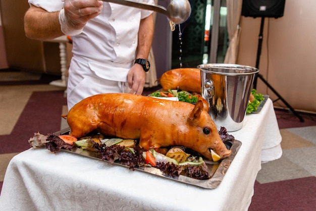 Menu del ristorante Maialino al forno intero su una tavola decorativa in pietra con frutta e physalis Vista dall'alto