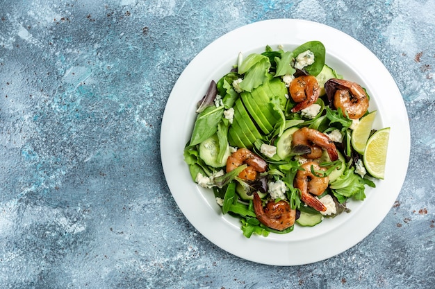 Menù dietetico. Insalata salutare con avocado, gorgonzola e gamberi affumicati. Cibo vegano. Disposizione piatta. Vista dall'alto.