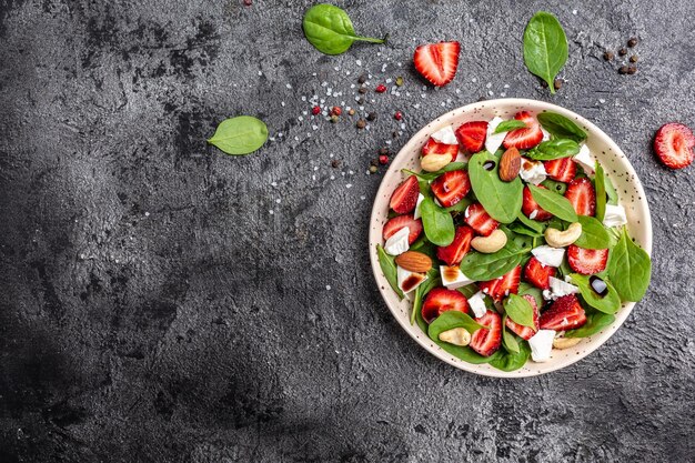 Menu dietetico Insalata sana di foglie fresche di spinaci alla fragola noci e formaggio feta aceto balsamico Cibo vegano Formato banner lungo vista dall'alto