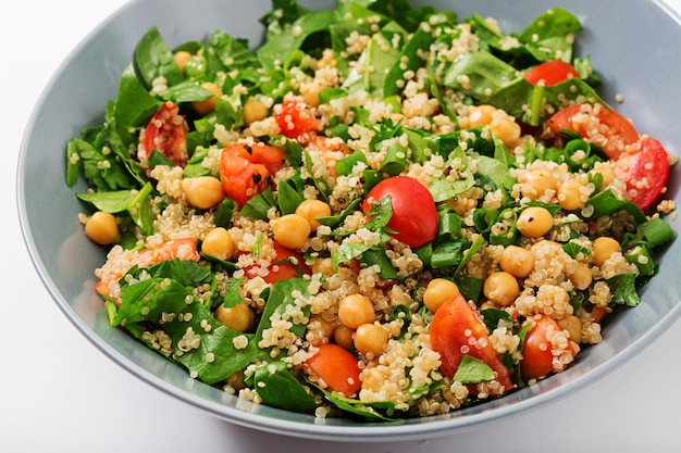Menu dietetico. Insalata vegana sana di verdure fresche - pomodori, ceci, spinaci e quinoa in una ciotola.