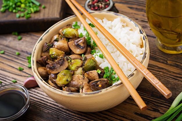 Menu vegano. Cibo dietetico. Riso bollito con funghi e cavoletti di Bruxelles in stile asiatico.