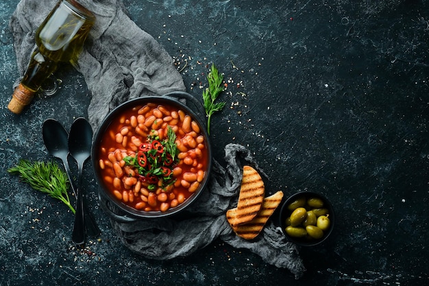 Menu vegetariano Fagioli stufati in salsa di pomodoro con prezzemolo e peperoncino In una ciotola nera Vista dall'alto Spazio libero per il testo