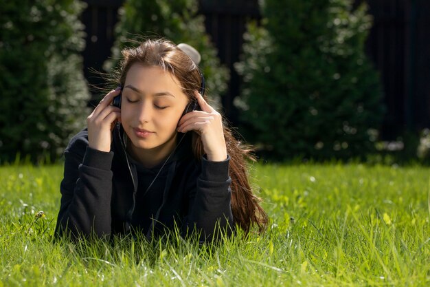 Menzogne castana dei capelli abbastanza lunghi sulla musica d'ascolto del prato inglese verde con le cuffie