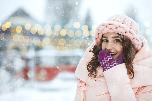 Meravigliosa donna sorridente godendo di nevicate alla fiera di natale. Spazio per il testo