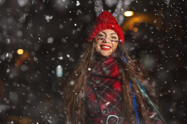 Meravigliosa giovane donna dai capelli lunghi che si gode il tempo nevoso alla fiera di Natale