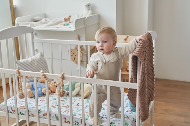 Meraviglioso bambino con gli occhi azzurri nella culla Bambino che gioca con i giocattoli nella scuola materna Asilo infantile dello sviluppo iniziale Sala giochi Festa dei bambini Festa della mamma