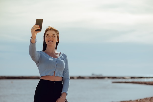 Meraviglioso giovane viaggiatore allegro e felice all'aperto fa un autoritratto con il cellulare in una giornata di sole