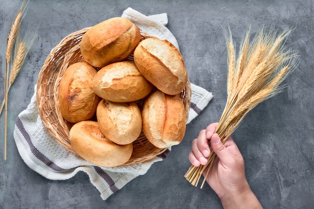 Merce nel carrello dei panini di pane su legno rustico con le orecchie del grano, vista superiore su gray