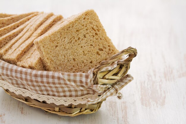 Merce nel carrello del pane sulla tavola di legno bianca