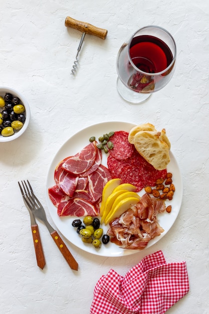 Merenda al vino. Prosciutto di Parma, prosciutto crudo, salame, mandorle, olive, baguette. Antipasti.