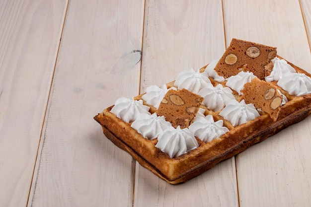 Meringa belga di waffle e chips di mandorle su fondo di legno chiaro