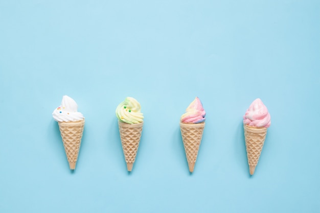 Meringa pastello sui coni gelati su fondo blu