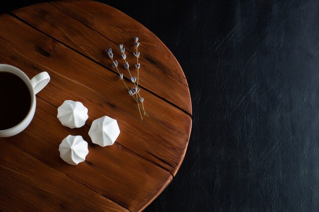 Meringhe bianche e tazza di caffè caldo su un tavolo in legno rustico.