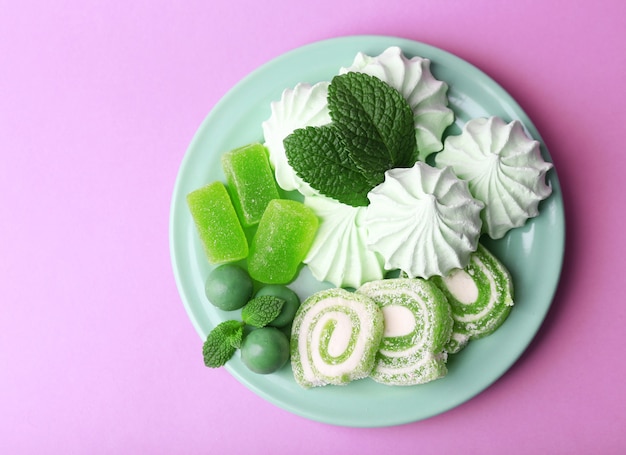 Meringhe color menta, caramelle alla menta e gustosa torta su sfondo colorato