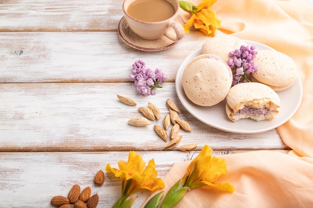 Meringhe torte con una tazza di caffè su una superficie di legno bianca e tessuto di lino arancione