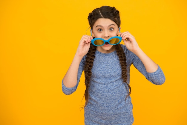 Meriti una grande cornice. sorpresa bella ragazza sorridente con l'acconciatura alla moda. sfondo giallo bambino spensierato. Emozioni positive alla festa. bambino che si diverte. Ritratto di ragazza felice in occhiali divertenti.