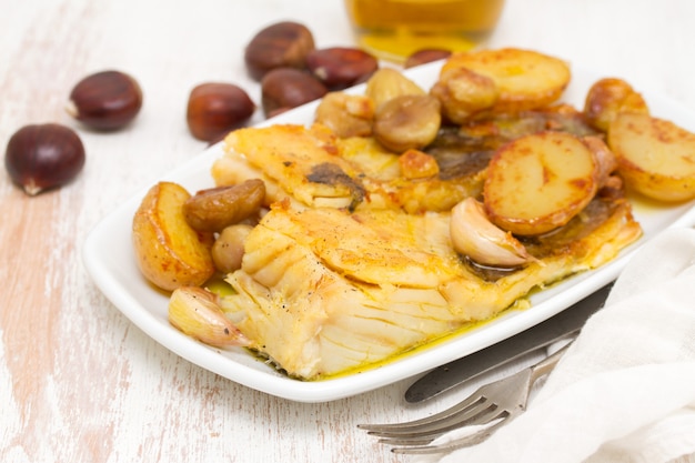 Merluzzo fritto con le castagne e la patata sul piatto bianco