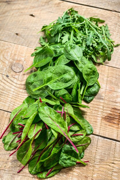 Mescolare foglie di insalata, rucola, spinaci e bietole. Fondo in legno. Vista dall'alto.