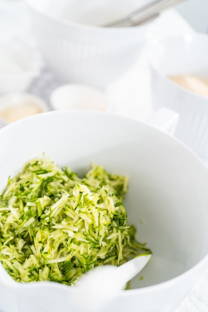 Mescolare gli ingredienti nella terrina per fare le torte di zucchine.