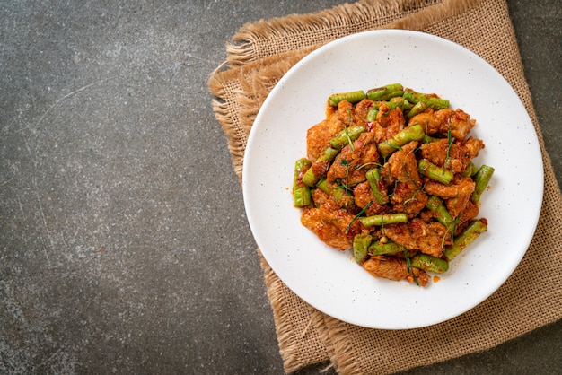 Mescolare il maiale fritto e la pasta di curry rosso con il fagiolo pungiglione