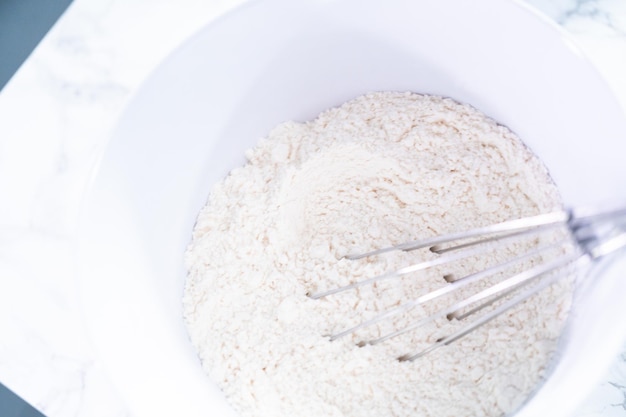 Mescolare la farina bianca e gli altri ingredienti secchi con una frusta in una ciotola bianca.