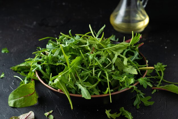 Mescolare le verdure per insalata. Rucola, lattuga, spinaci in una ciotola nera