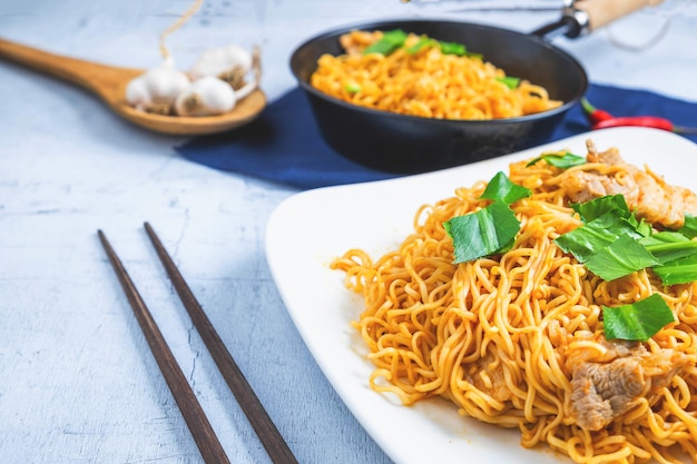 Mescolare tagliatelle con verdure in un piatto bianco su un pavimento di legno.