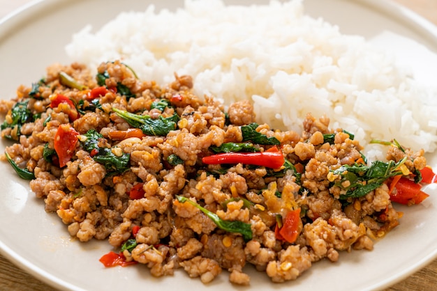 Mescoli il basilico tailandese fritto con carne di maiale tritata su riso sormontato