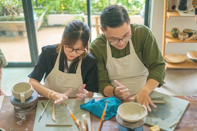 Messa a fuoco giovane vasaio che lavora sul tornio del vasaio rendendo vaso di ceramica da argilla nel laboratorio di ceramica Coppia innamorata che lavora insieme nel laboratorio di vasaio