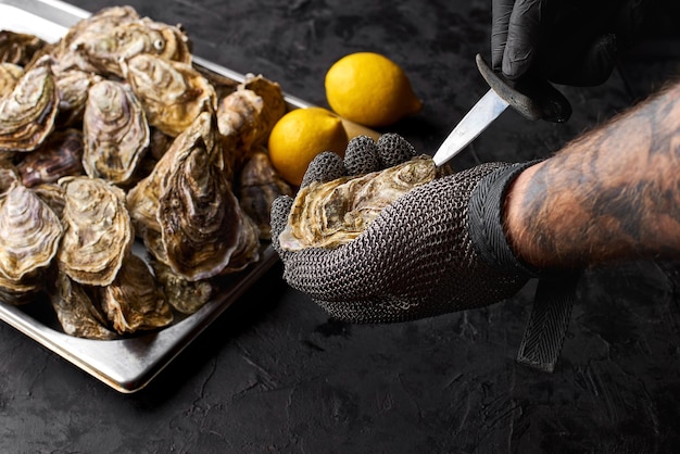 Messa a fuoco selettiva a portata di mano preparare ostriche fresche sul bancone della bancarella di frutti di mare nel mercato