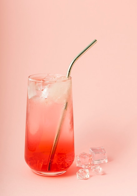 Messa a fuoco selettiva, bibita analcolica, limonata con ghiaccio rosa su sfondo rosa, con tubo di metallo