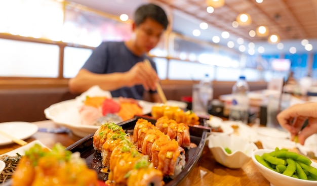 Messa a fuoco selettiva cibo giapponese in un ristorante giapponese sushi di salmone con uomo sfocato che mangia cibo