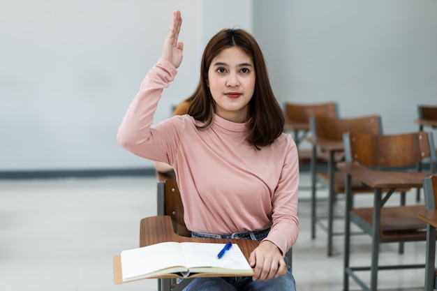 Messa a fuoco selettiva degli studenti universitari adolescenti seduti sulla sedia della lezione in aula scrivere sul foglio di risposta della carta d'esame nel fare il test dell'esame finale. Studentesse in uniforme studentesca.