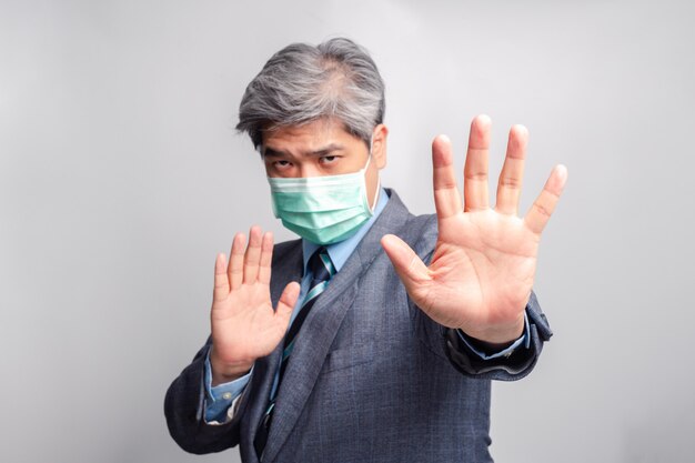 Messa a fuoco selettiva della mano. Ritratto di uomo d'affari asiatico con mascherina medica chirurgica guardando la fotocamera