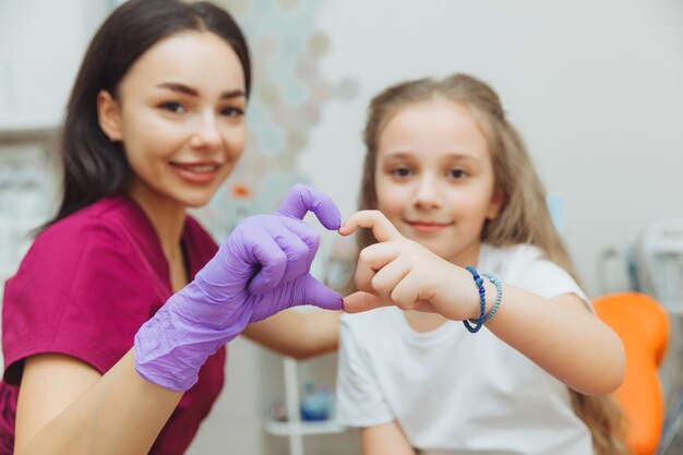 Messa a fuoco selettiva delle mani del dentista e della bambina paziente a forma di cuore