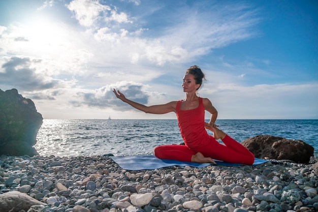 Messa a fuoco selettiva giovane bella donna caucasica in un abito rosso che pratica yoga fitness e stretching