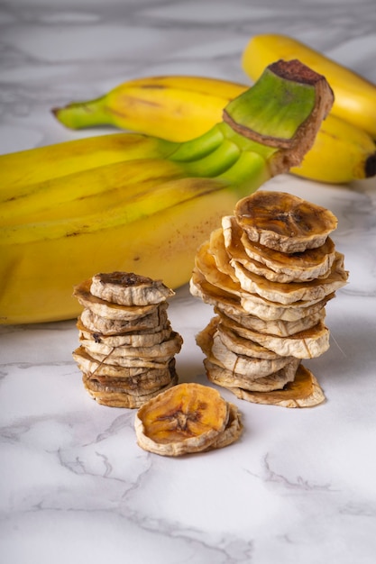 messa a fuoco selettiva, spuntino sano, fette di banana essiccate su uno sfondo chiaro con frutta banana matura