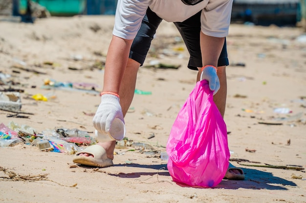 Messa a fuoco Uomo volontario che indossa guanti che raccolgono i rifiuti delle bottiglie sulla spiaggia del parco Pulizia della natura