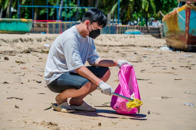 Messa a fuoco Uomo volontario che indossa guanti che raccolgono i rifiuti delle bottiglie sulla spiaggia del parco Pulizia della natura