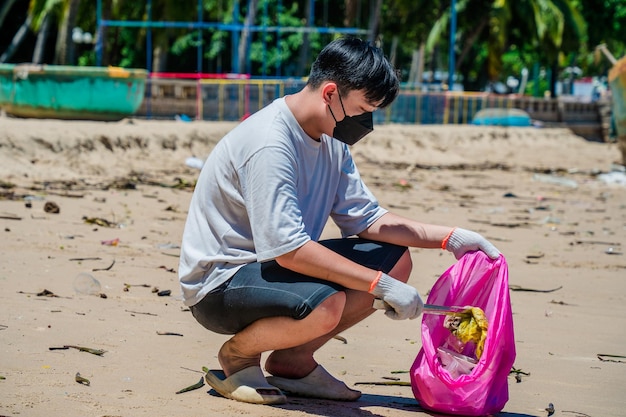 Messa a fuoco Uomo volontario che indossa guanti che raccolgono i rifiuti delle bottiglie sulla spiaggia del parco Pulizia della natura