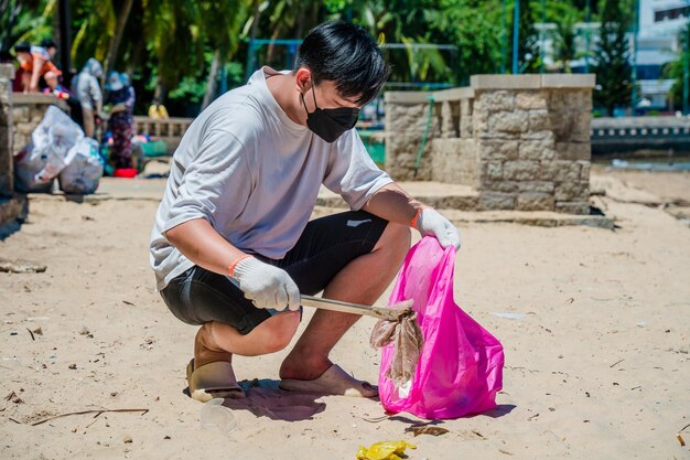 Messa a fuoco Uomo volontario che indossa guanti che raccolgono i rifiuti delle bottiglie sulla spiaggia del parco Pulizia della natura