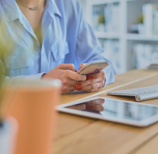 Messaggi di testo della giovane donna d'affari mentre è seduto in ufficio davanti al computer portatile