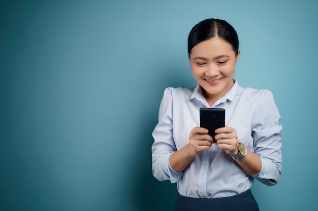 Messaggio di battitura felice della donna asiatica con il telefono astuto isolato sopra.